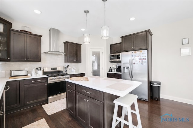 kitchen featuring stainless steel appliances, dark wood-style floors, wall chimney exhaust hood, and dark brown cabinets