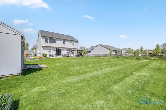 rear view of house featuring fence, a wooden deck, a gazebo, and a lawn