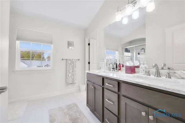 bathroom with double vanity, a sink, lofted ceiling, and a shower