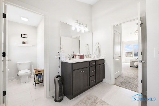 full bathroom with a sink, tile patterned flooring, double vanity, toilet, and a ceiling fan