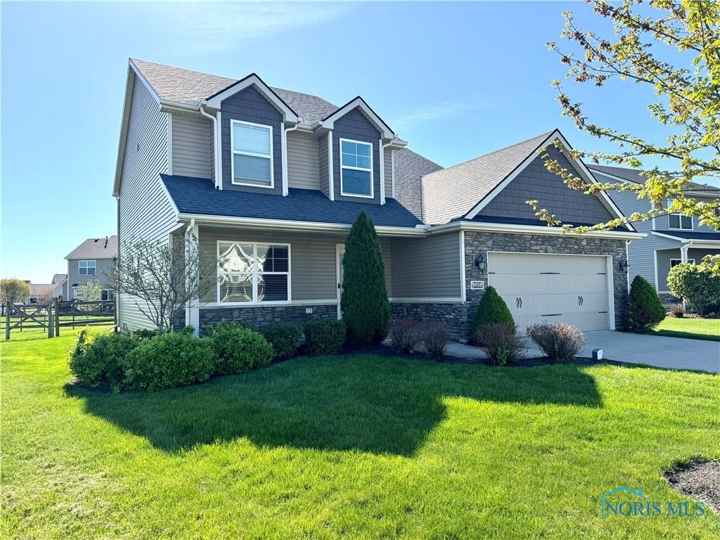 craftsman-style house with a front lawn, a garage, stone siding, concrete driveway, and fence