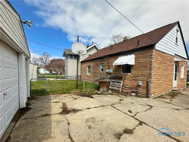 4865 296th St, Toledo, OH 43611 - back of house featuring a garage, a shingled roof, and fence