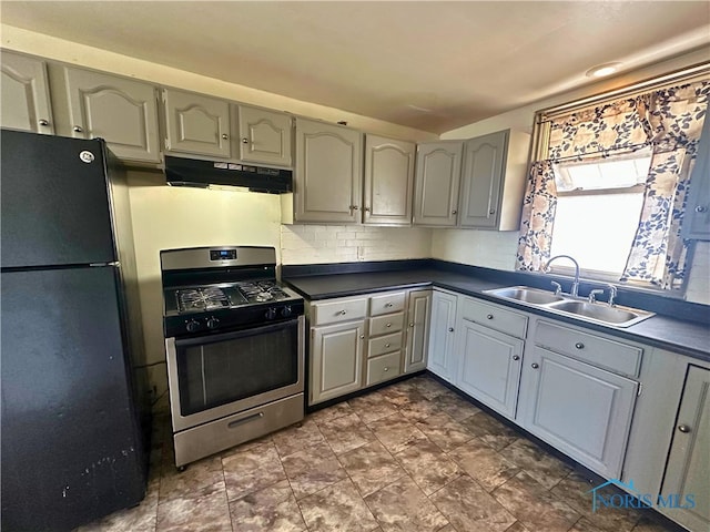 4865 296th St, Toledo, OH 43611 - kitchen with freestanding refrigerator, under cabinet range hood, dark countertops, a sink, and stainless steel gas range
