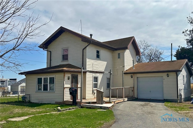 traditional-style home with aphalt driveway, a deck, fence, a front lawn, and a garage