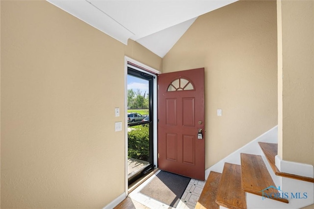 foyer entrance with stairway and vaulted ceiling