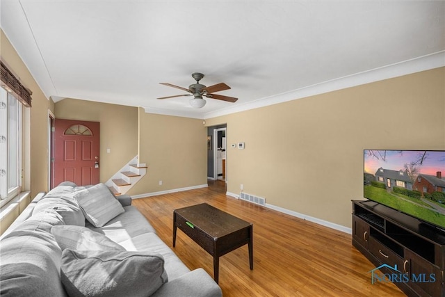 living area featuring visible vents, stairs, ceiling fan, baseboards, and light wood-type flooring