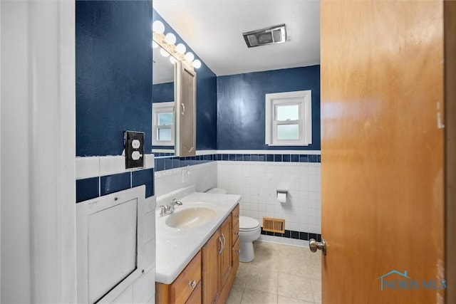 bathroom with visible vents, toilet, tile walls, tile patterned floors, and vanity