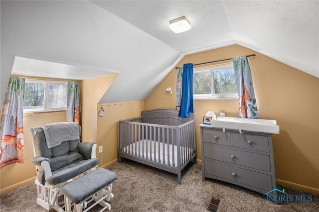 carpeted bedroom featuring baseboards, visible vents, a crib, and lofted ceiling