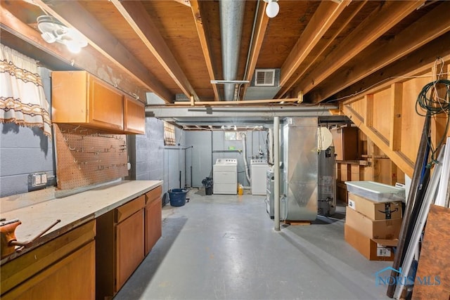 below grade area with visible vents, separate washer and dryer, concrete block wall, and gas water heater