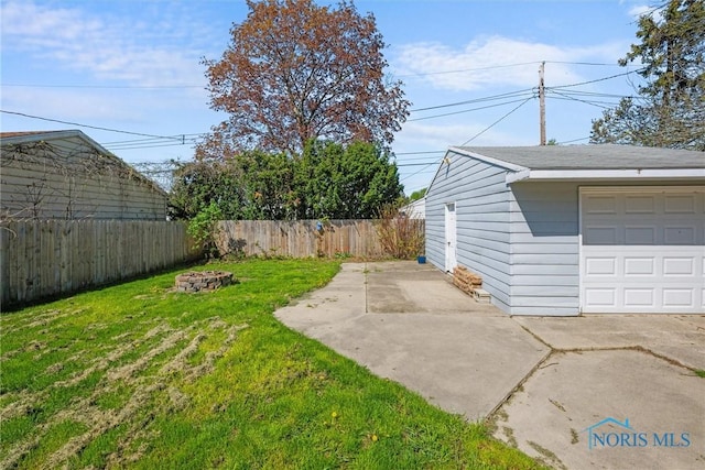 view of yard with a garage, a fire pit, and a fenced backyard