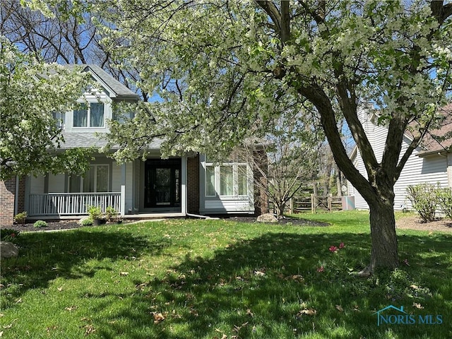 exterior space with a yard, covered porch, and brick siding