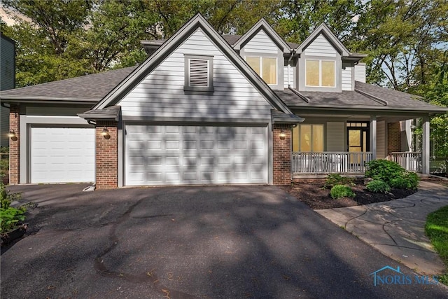 544 Jacqueline Ct, Holland, OH 43528 - view of front facade featuring brick siding, an attached garage, asphalt driveway, covered porch, and roof with shingles