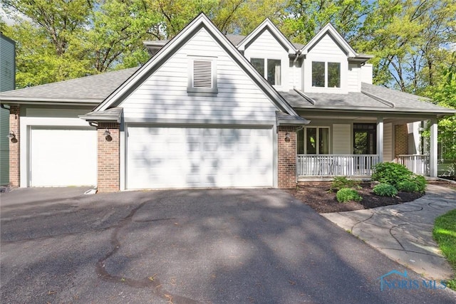 544 Jacqueline Ct, Holland, OH 43528 - view of front of home with brick siding, a porch, asphalt driveway, and a garage
