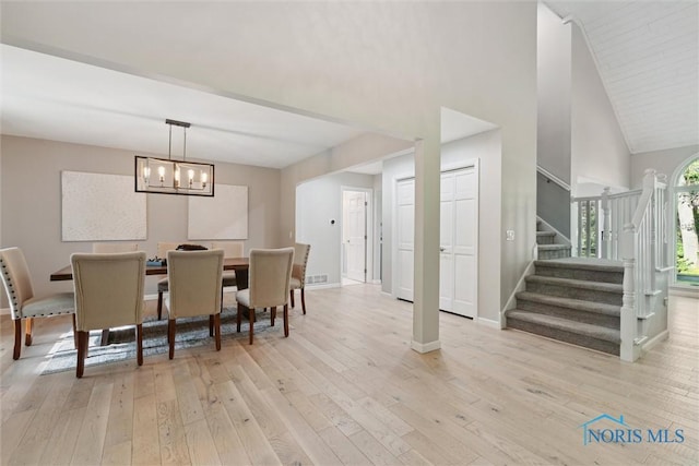 544 Jacqueline Ct, Holland, OH 43528 - dining room with light wood-style floors, stairs, a chandelier, baseboards, and high vaulted ceiling