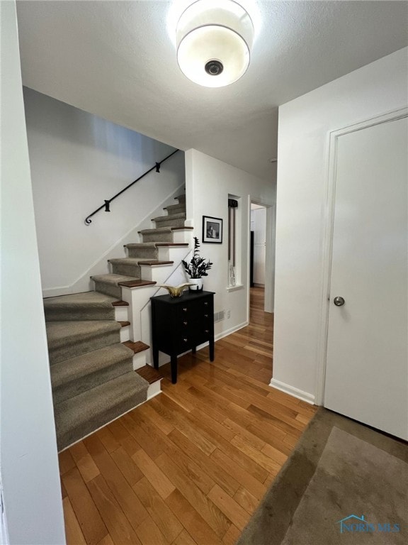 stairway featuring wood finished floors and baseboards