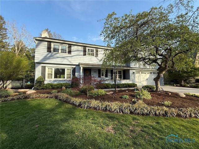 traditional home with a front yard, driveway, a chimney, an attached garage, and fence