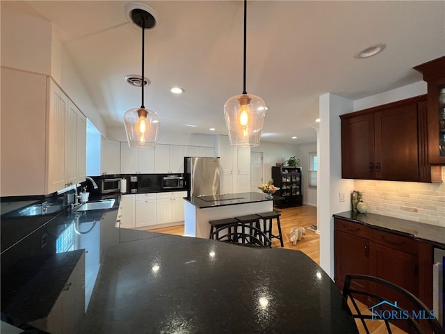 kitchen featuring backsplash, black microwave, recessed lighting, and freestanding refrigerator