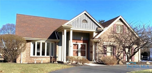 view of front of house with a front yard, board and batten siding, and brick siding