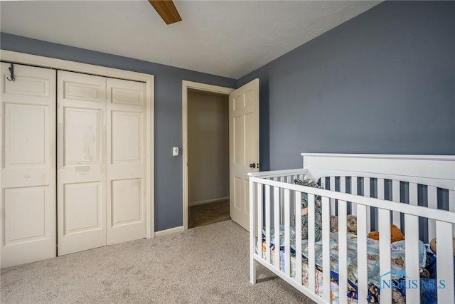 carpeted bedroom with a closet, baseboards, ceiling fan, and a nursery area