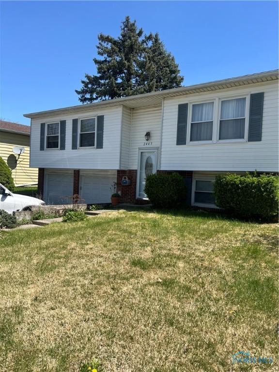 raised ranch featuring a front lawn and a garage
