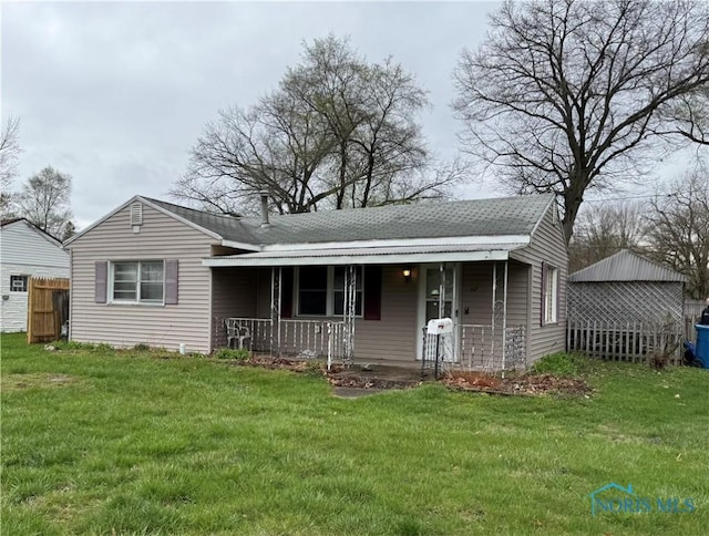 view of front of house featuring covered porch, fence, and a front lawn