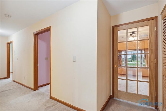 hallway featuring baseboards and light colored carpet