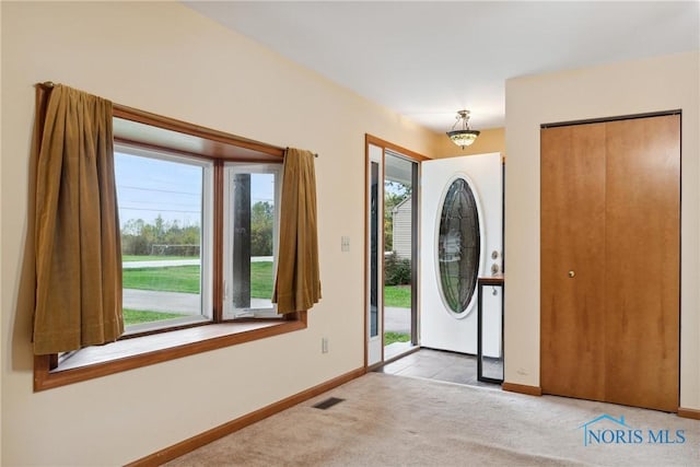 foyer with visible vents, carpet, and baseboards