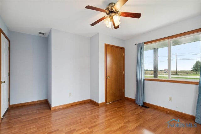 unfurnished bedroom featuring baseboards, visible vents, ceiling fan, and light wood finished floors