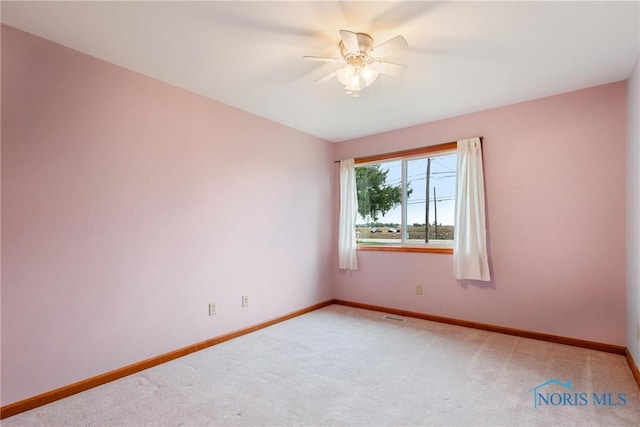 carpeted spare room with baseboards, visible vents, and ceiling fan