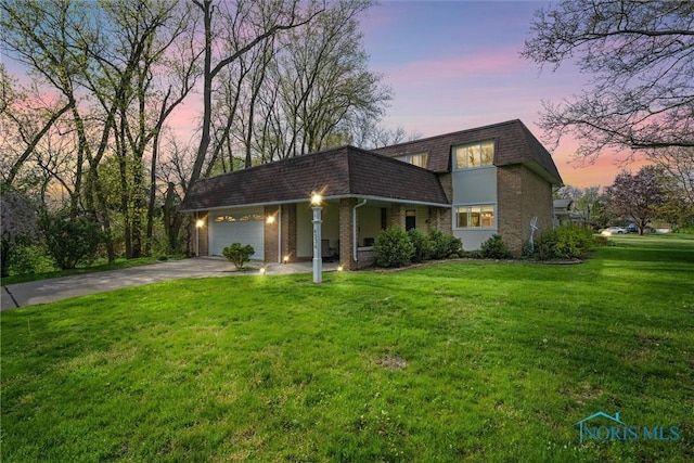 view of front of property featuring a garage, a front yard, mansard roof, brick siding, and driveway