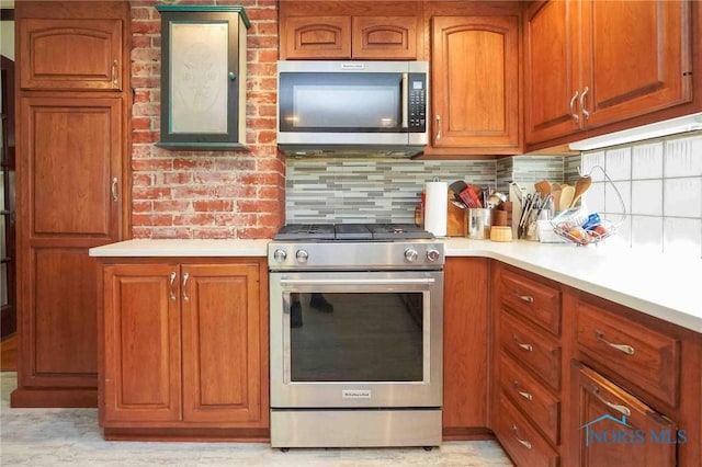 202 Hancock St, Findlay, OH 45840 - kitchen featuring appliances with stainless steel finishes, light countertops, brown cabinets, and tasteful backsplash