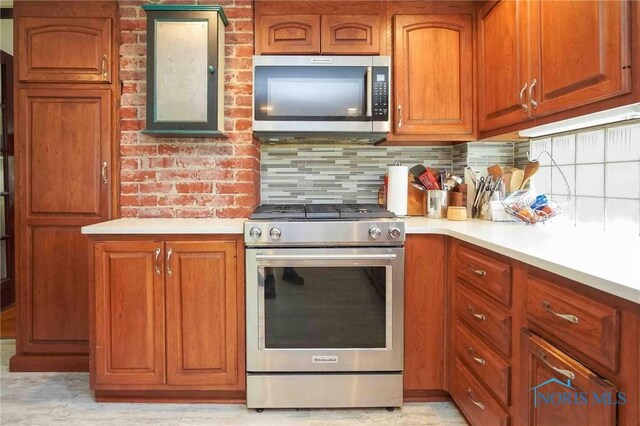 202 Hancock St, Findlay, OH 45840 - kitchen featuring stainless steel appliances, light countertops, brown cabinets, and backsplash