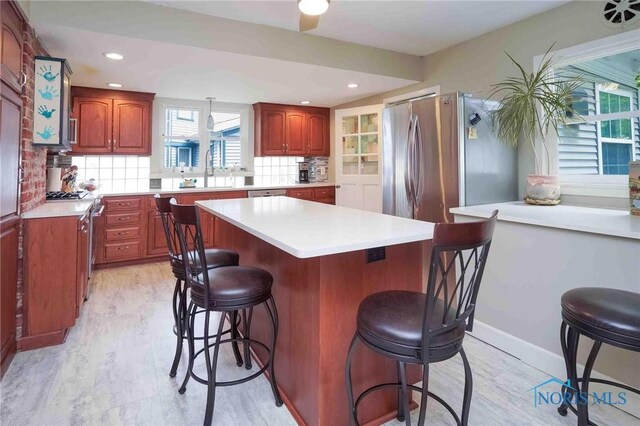 202 Hancock St, Findlay, OH 45840 - kitchen with a breakfast bar area, a center island, light countertops, tasteful backsplash, and appliances with stainless steel finishes
