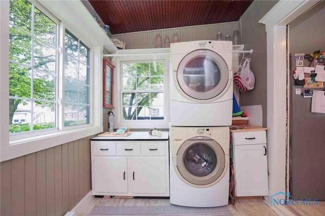 202 Hancock St, Findlay, OH 45840 - washroom with stacked washing machine and dryer, cabinet space, wood walls, wood ceiling, and light wood-style floors