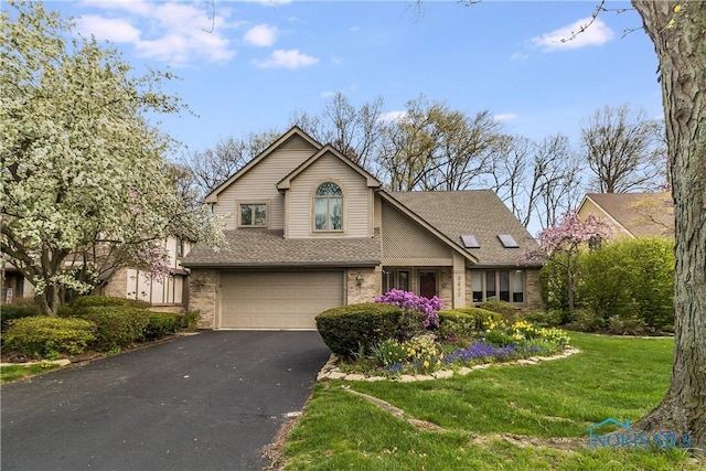 traditional-style home with a front yard, brick siding, aphalt driveway, an attached garage, and a shingled roof