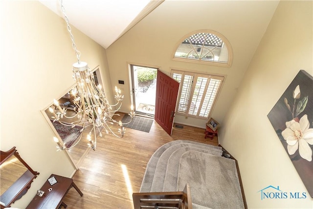 foyer featuring visible vents, wood finished floors, a chandelier, and high vaulted ceiling
