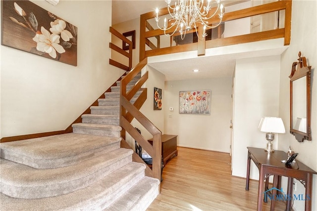 stairs with baseboards, a high ceiling, wood finished floors, and a notable chandelier