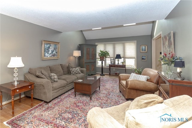 living room featuring light wood-style floors, baseboards, and vaulted ceiling