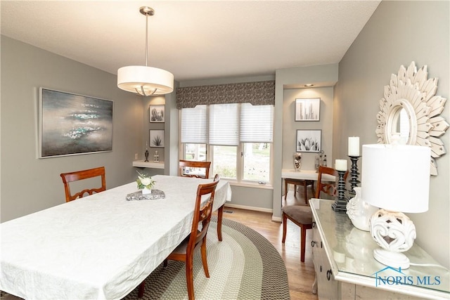 dining area with baseboards and light wood finished floors