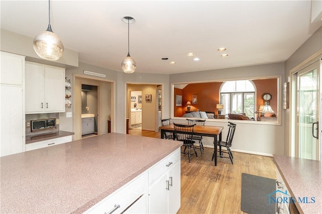kitchen featuring white cabinets, pendant lighting, and light wood-style floors