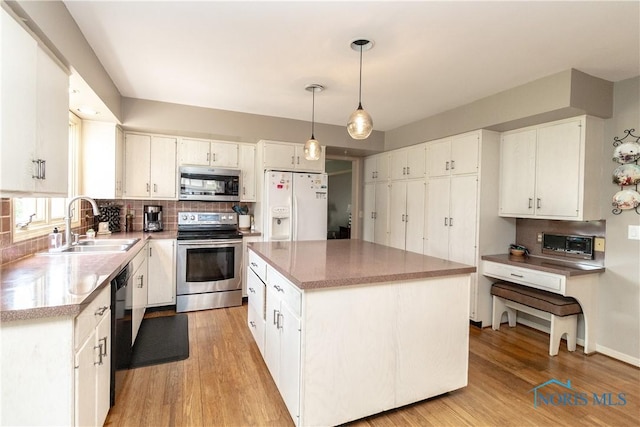 kitchen with stainless steel appliances, decorative backsplash, a sink, and light wood finished floors