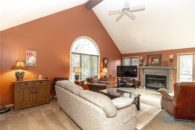 living room featuring high vaulted ceiling, a glass covered fireplace, light carpet, and ceiling fan