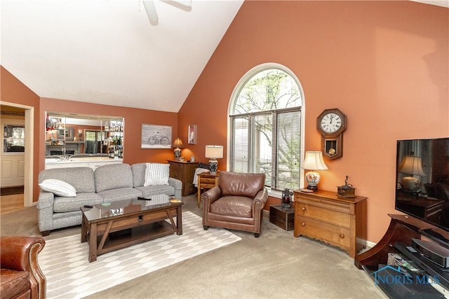 carpeted living room with ceiling fan and high vaulted ceiling