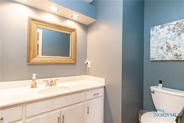 half bathroom featuring vanity and toilet