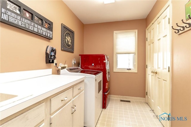 clothes washing area with baseboards, washer and clothes dryer, cabinet space, and visible vents