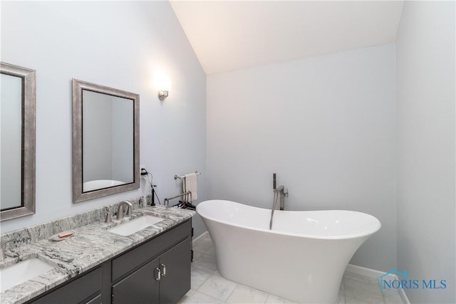 bathroom featuring a sink, a soaking tub, double vanity, and lofted ceiling