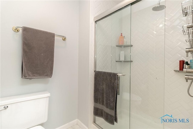 full bathroom with baseboards, a shower stall, and toilet