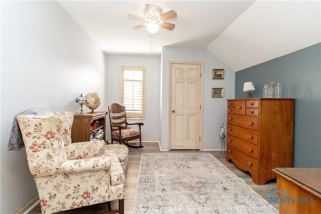 sitting room featuring baseboards, ceiling fan, light wood finished floors, and lofted ceiling