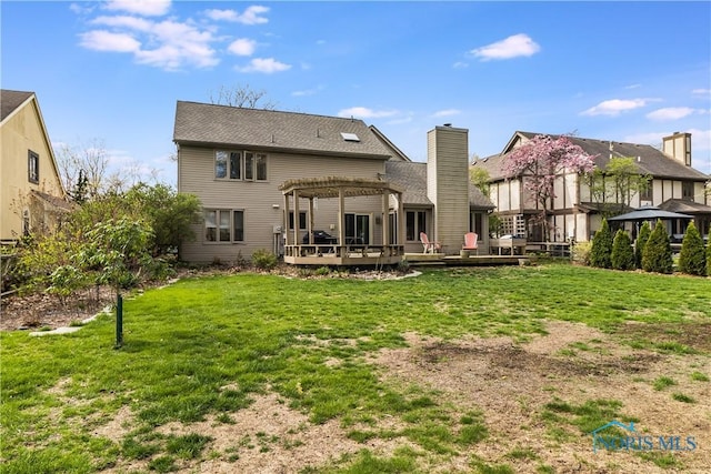 rear view of property with a wooden deck, a pergola, and a yard