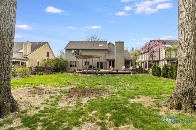 back of property featuring a chimney, a yard, a pergola, and a deck